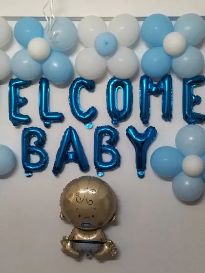 A simple wall decoration to welcome a baby. This includes 'Welcome Baby' foil letters, a baby-shaped foil balloon, and classic blue and white balloon clusters.