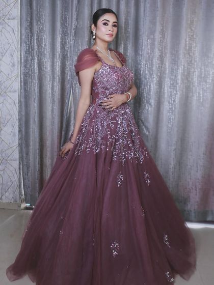 A full-length view of the mauve-purple gown, highlighting its voluminous skirt and elegant off-shoulder sleeves.