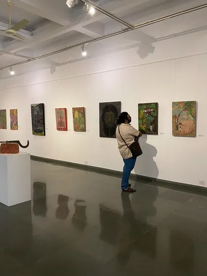 A visitor looking closely at one of Unnikrishnan C's more somber portraits.