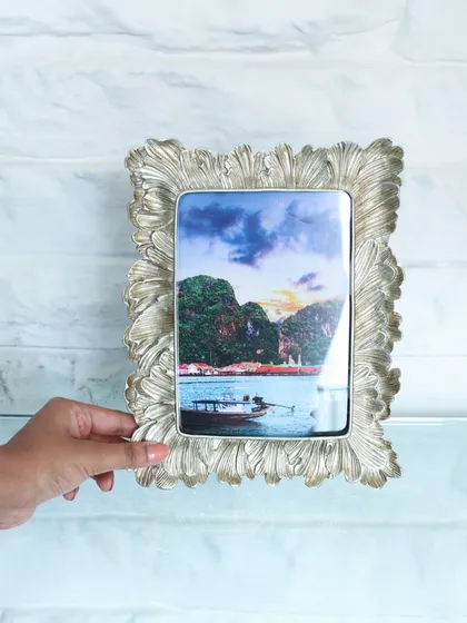 A hand holding our silver photo frame with a delicate, leaf-like texture. The antique silver finish gives it a timeless appeal, perfect for any cherished memory.