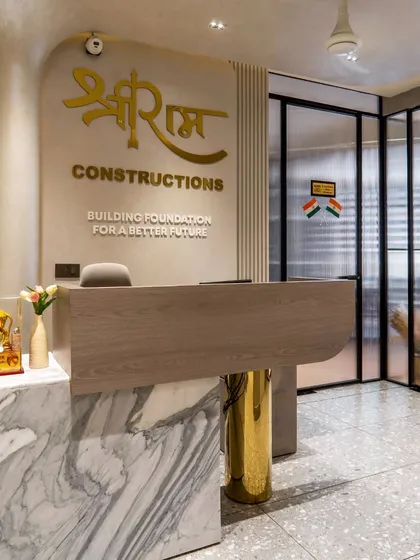 The reception desk, with its combination of veined marble, wood, and a polished gold-finished leg. The company's logo is prominently displayed in a matching gold finish, creating a strong brand statement.