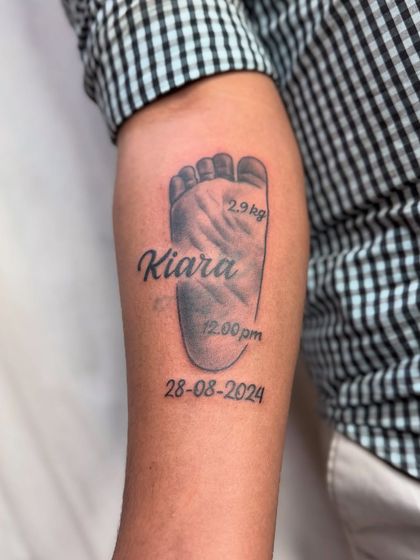 Another angle of the baby footprint tattoo, showing how it wraps slightly around the arm.