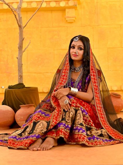 A full-body shot showing the complete Rajasthani look. The barefoot pose and the arrangement of props create a very natural and story-driven scene.