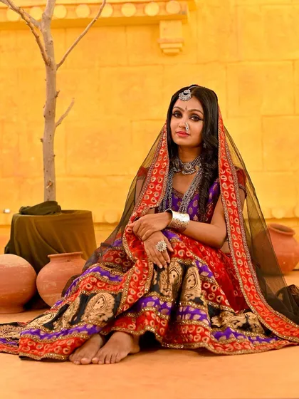 A full-body shot showing the complete Rajasthani look. The barefoot pose and the arrangement of props create a very natural and story-driven scene.
