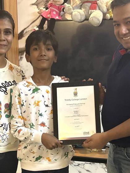 **A Proud Moment.** A student proudly receives his Trinity College London certificate from our mentor, with his mother by his side. We celebrate these achievements as a team.