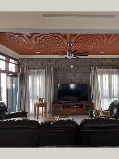 A comfortable living room with a stone accent wall and a terracotta filler ceiling, demonstrating the mix of rugged and refined textures.
