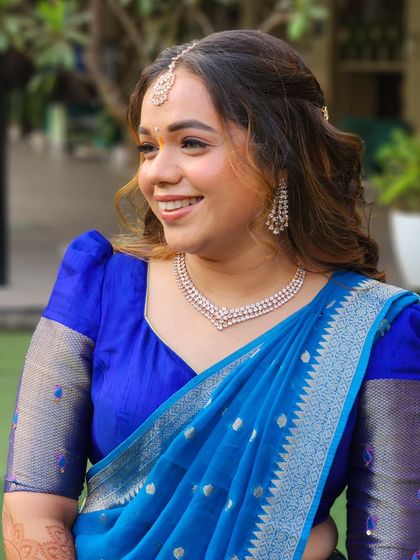 A happy and radiant bride in her blue engagement outfit. The makeup is minimal and fresh, highlighting her natural glow.