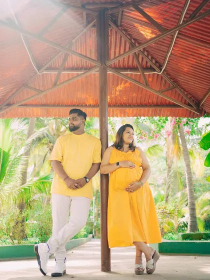 Finding interesting structures in an outdoor location can add a unique touch to your photos. Here, the couple poses under a shaded gazebo, creating a relaxed and stylish portrait during their maternity session.