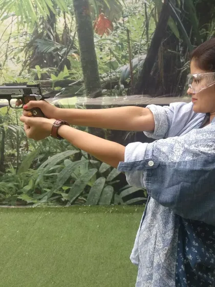 A visitor enjoying her first practical shooting experience with a pistol. Our instructors are always on hand to guide you on proper grip and stance for a safe and enjoyable session.
