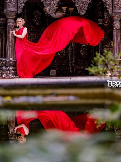 A beautiful reflection shot of a model in a red dress against our ornate wooden doors.