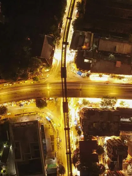 A top-down, long-exposure drone shot of a flyover in Mumbai at night, with the traffic's light trails creating a "warp speed" effect.
