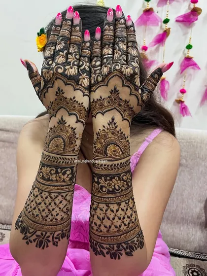 A beautiful pose showcasing a full coverage back-hand bridal design. The pattern features classic jaali work, floral bands, and scalloped edges for a rich and complete look.