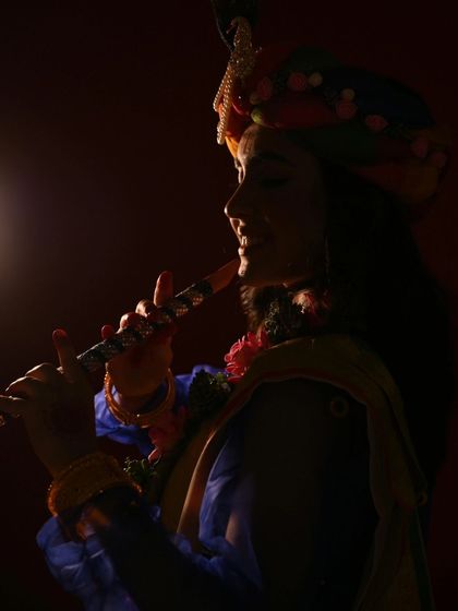 A silhouette of Krishna playing his flute. The dramatic lighting creates a mystical and divine atmosphere, focusing on the iconic symbol of his music.