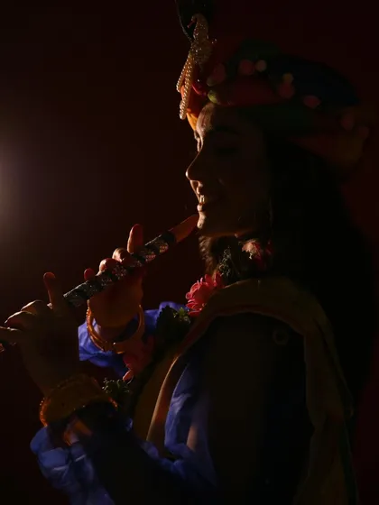 A silhouette of Krishna playing his flute. The dramatic lighting creates a mystical and divine atmosphere, focusing on the iconic symbol of his music.