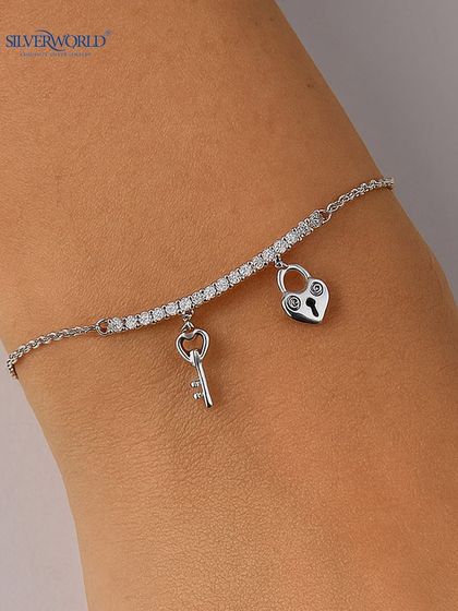 This charming bracelet features a zirconia-studded bar with dangling lock and key charms. It's a romantic and playful piece, perfect as a gift.
