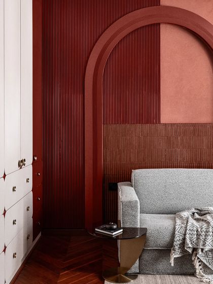 The guest bedroom in Scarlet Horizon is a playful yet refined space. We used a bold red accent wall with layered textures and arches to create visual interest, while the simple grey sofa provides a neutral counterpoint.