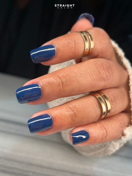 A bold and beautiful glossy navy blue on shorter, square-shaped nails. This deep color is a chic and modern alternative to black.
