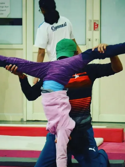 A coach helps a student with a flexibility exercise, demonstrating our hands-on approach to training.