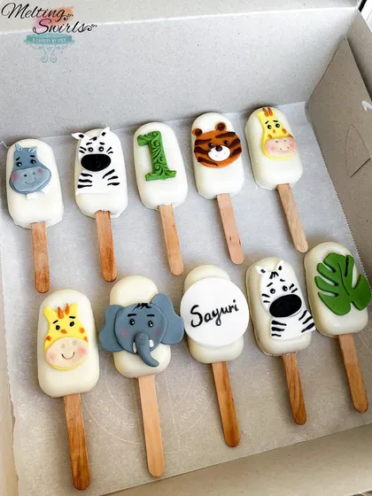 A closer look at the jungle themed cakesicles we made for Sayuri's first birthday. The set includes adorable, hand-decorated animal faces like a hippo, zebra, tiger, and elephant, plus a personalized one with her name.