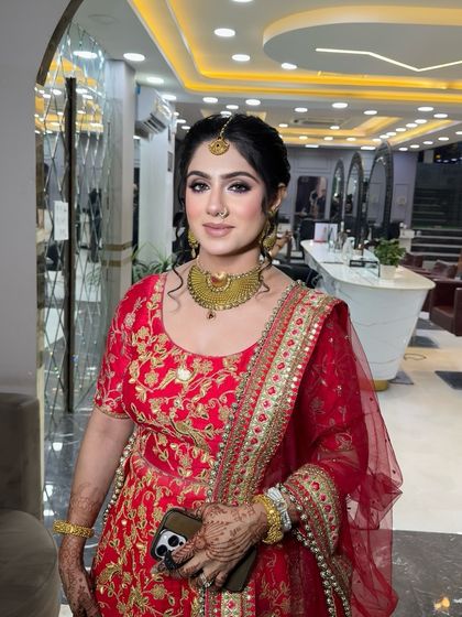 This bride is glowing in her red lehenga. The makeup highlights her features with a focus on the eyes, paired with a traditional bridal nose ring and maang tikka.