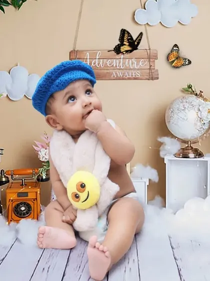 An 'Adventure Awaits' themed shoot for a seven-month-old baby boy. Props like a globe, vintage telephone, and a pilot's scarf create a story within the photo.