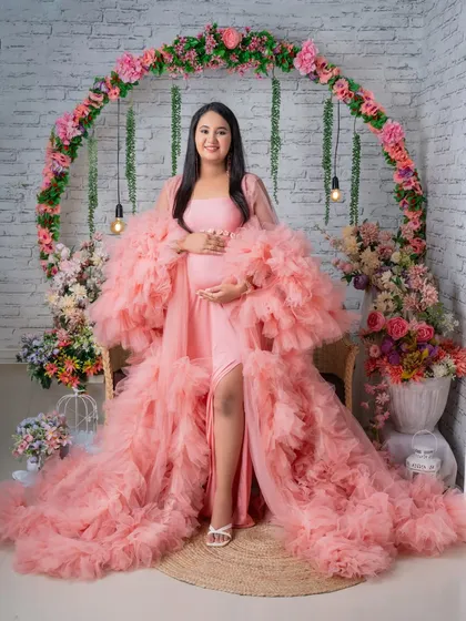 Our popular pink ruffled gown set against a beautiful floral arch. This setup is perfect for a romantic and feminine maternity photoshoot.