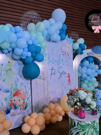 A close-up of the balloon garland and backdrop, showing the mix of different shades of blue and the cute illustrated sea creatures.