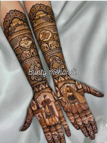 This full-arm bridal mehendi features a classic Dulha-Dulhan portrait on the palms, surrounded by traditional Rajasthani patterns and animal motifs.