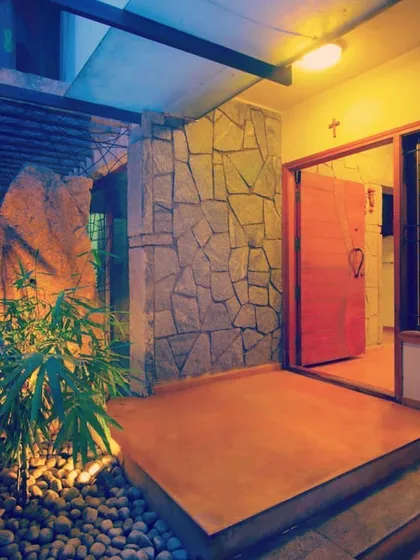 The entrance to a residence, designed to create a welcoming transition from the outside in. The use of natural stone, warm up-lighting on the plants, and a bold red door creates an entry that is both dramatic and intimate.