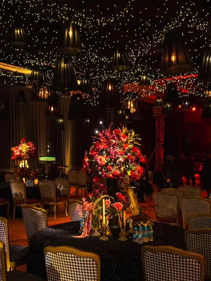 Glamorous seating for a cinematic reception. The houndstooth-patterned chairs and tablescapes with heavy floral centerpieces were set against a backdrop of dramatic lighting and a starlit ceiling.