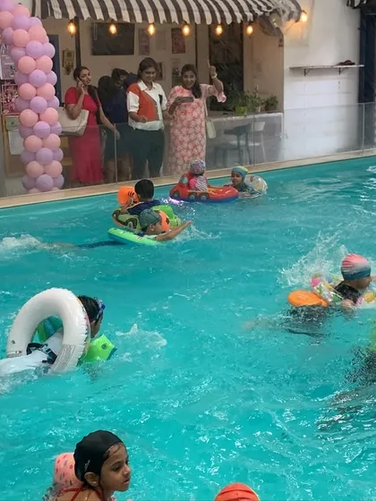 Kids enjoying the water with ring floats and other toys. The glass partition ensures a clear view of the pool from the surrounding party area.