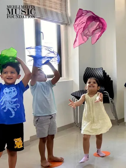 The pure, uninhibited joy of music and movement in our Discover Music class. We use colorful props like these scarves to help our youngest students feel the rhythm and express themselves, making learning an exciting and playful experience.