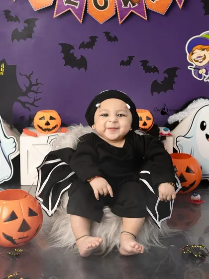 A happy little bat, smiling from his fluffy seat. The contrast between the dark costume and his bright smile is just adorable.