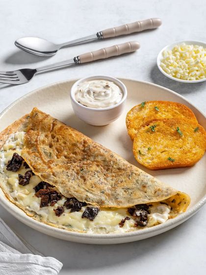 A cheese and mushroom omelette, with a focus on the melted cheese oozing from the fold.