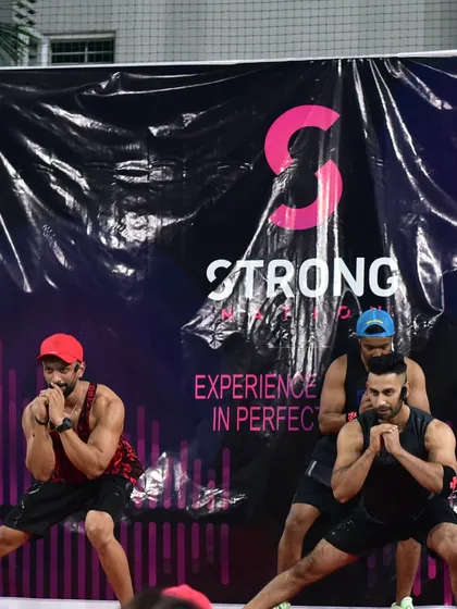 Demonstrating a synchronized lunge on stage during a Strong Nation event. The power of this format comes from the entire group moving as one, driven by the music.
