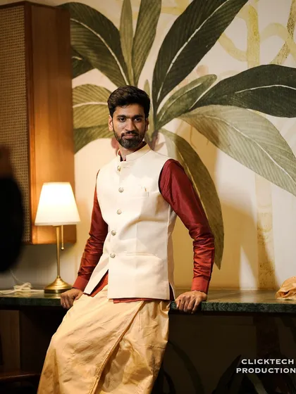 A stylish portrait of the groom in his wedding attire, a mix of a traditional dhoti and a modern waistcoat.