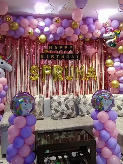 A full unicorn-themed room decoration using a purple and pink color scheme. The setup includes a balloon arch framing a shimmer backdrop, multiple unicorn foil balloons, and balloon columns to transform the space.
