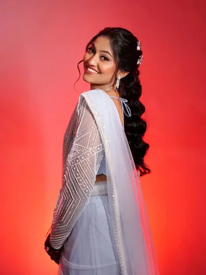 A joyful, over-the-shoulder smile. This candid moment captures the beauty of her complete look, from the hairstyle to the glowing makeup.