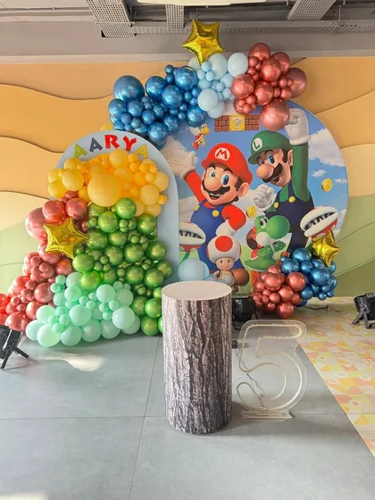 It's-a-me, Mario! A Super Mario Bros theme for a 5th birthday, featuring character backdrops and colorful balloon clusters representing the game's world.