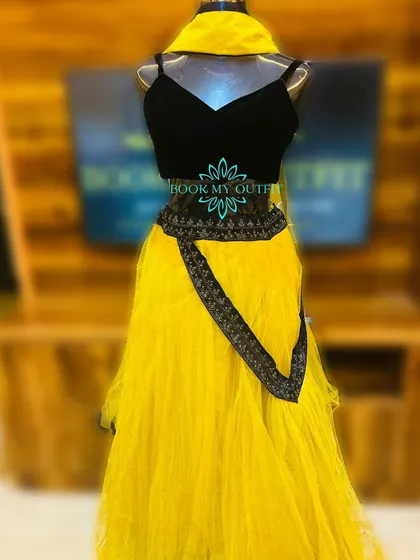 I have a special collection of outfits for Haldi ceremonies. This bright yellow net lehenga with a simple black blouse and embroidered belt is a popular rental choice for pre-wedding functions and photoshoots.