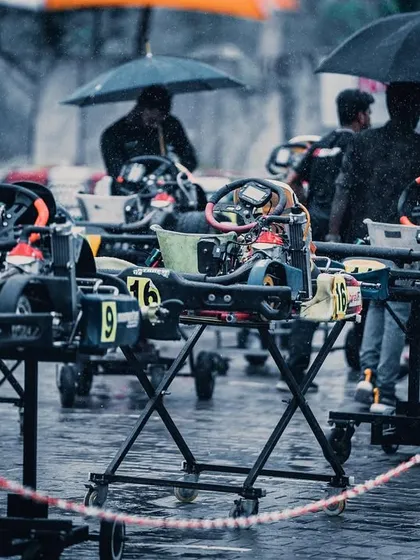 A chaotic but controlled scene in the pit lane during a wet race.
