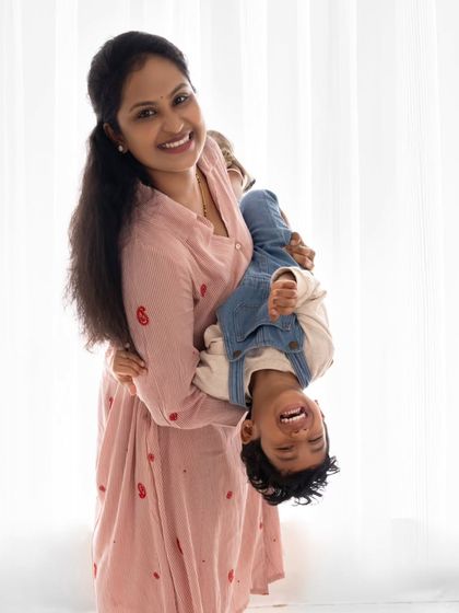 A mother holding her son upside down, both sharing a laugh. Capturing these playful moments is a joy.