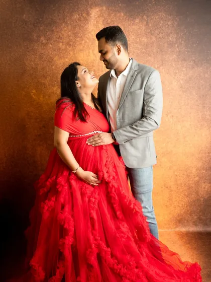 A classic studio portrait against a warm, textured backdrop. The pose is intimate, capturing the couple looking at each other with affection.