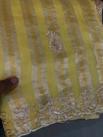 A sunny yellow tissue stripes organza saree with a paisley buti and detailed embroidery on the border.