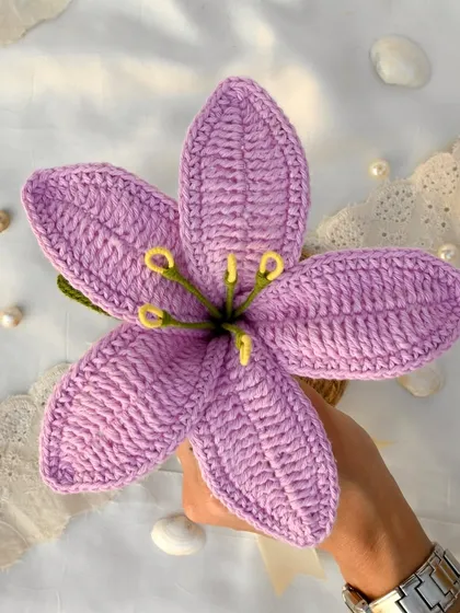 A single purple crochet lily held in hand. The rich color and detailed craftsmanship make this a truly special piece.