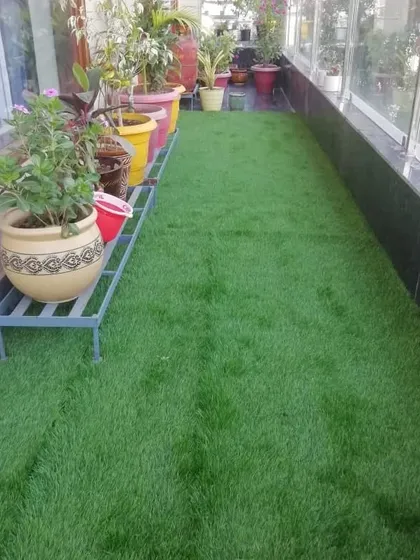 Even a very narrow balcony can be made beautiful and usable with artificial grass and a rack for plants.