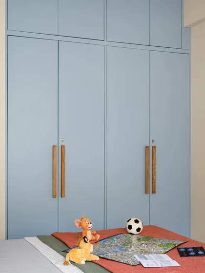 A full view of the kids' room wardrobe in a soft blue finish, featuring custom elongated wooden handles that are easy for children to use.