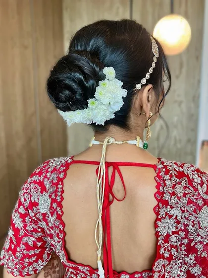 A sleek and polished bridal bun with a few white flowers for a touch of simplicity and grace. This look is perfect for the minimalist bride.