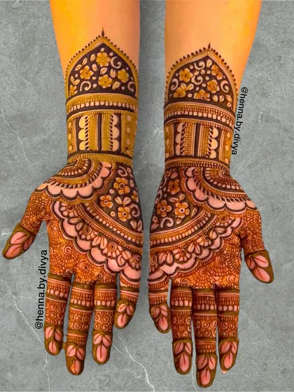 A beautiful example of Indian mehendi with a scalloped pattern on the palms. The wrists are adorned with a dome-shaped design filled with floral motifs.