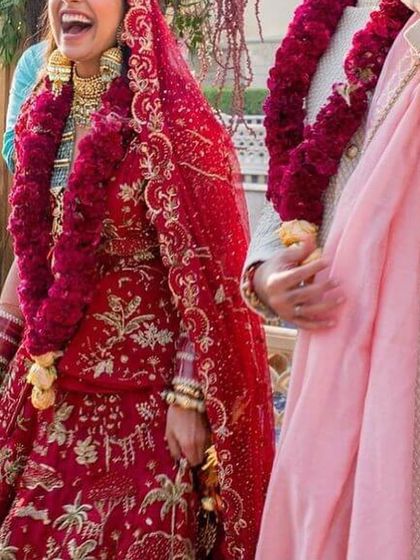 This full-length view shows the impact of a thick, handcrafted red rose varmala. I ensure each garland is lush and vibrant, making it a central part of your wedding look.